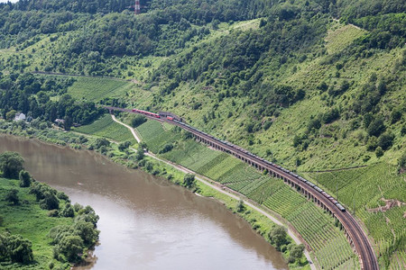 客运列车和货在沿德国Moselle河的铁路轨迹上相通过图片