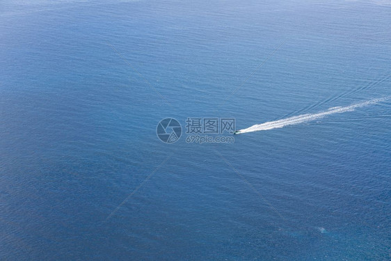 一小艘船在无尽的蓝海中航行空景象图片