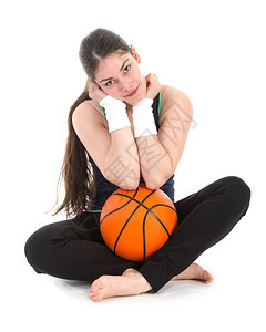 运动中的漂亮年轻女子穿着运动服坐在地板上带着篮球图片