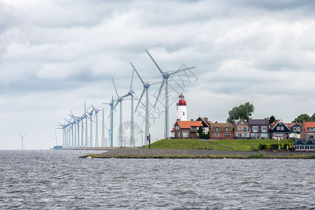 荷兰捕渔村乌尔克海风涡轮机在房屋的天线上空升起乌尔克海景村风涡轮机在房屋上升起图片