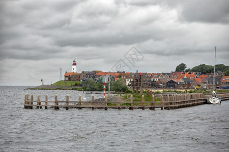 荷兰捕渔村乌尔克Urk海景港口入处有木制码头乌尔克海景村风力涡轮机在房屋上方升起图片