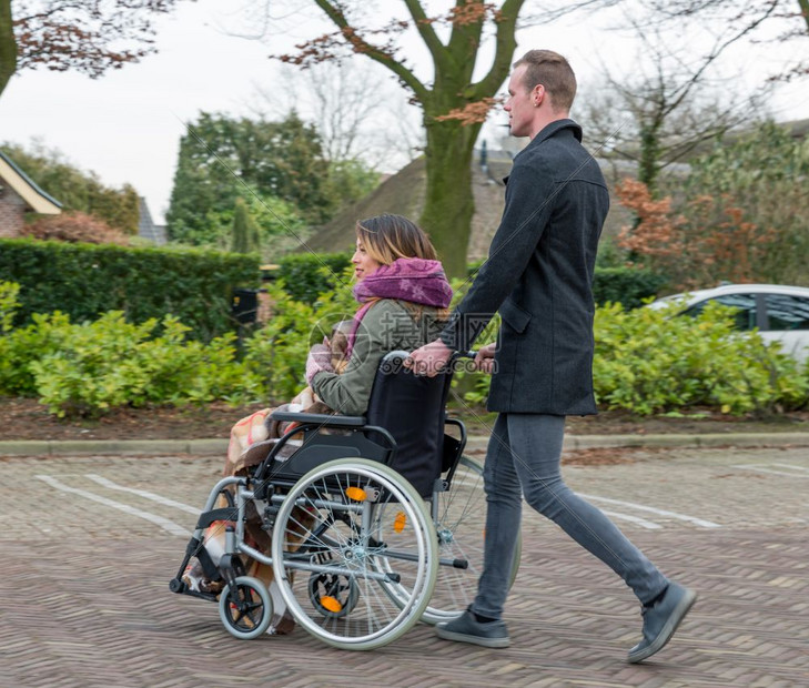 男子在荷兰村的停车场将妇女推上轮椅