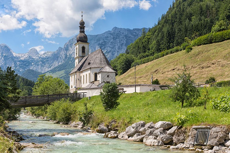 德国巴伐利亚阿尔普斯Berchtestesgaden附近的拉姆苏教堂前面有一条河流和木桥图片