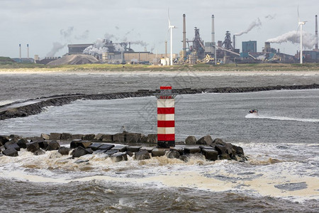 荷兰的IJmuiden码头有灯塔和暴海背景是钢铁厂图片