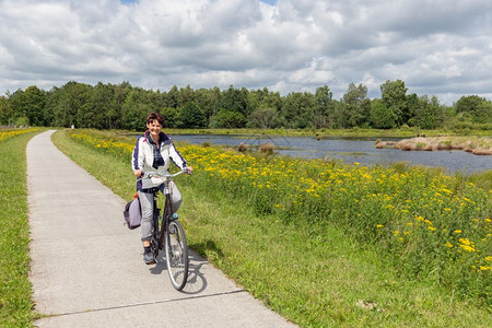 荷兰公园中带有森林和湿地的骑自行车妇女图片