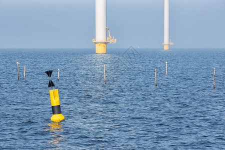 荷兰海岸附近有离风力涡轮机有浮标和捕鱼网杆的离岸风力涡轮机日落荷兰海岸附近有浮标的离岸风力涡轮机图片