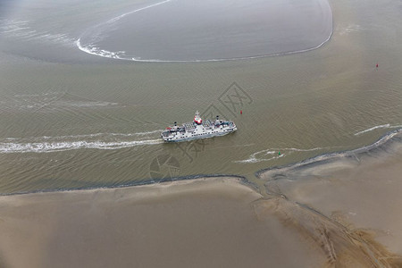 荷兰渡船在WaddenSea的荷兰渡船在WaddenSea通过沙岸之间的小通道低潮航行图片