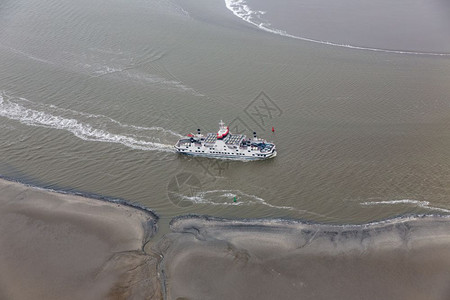 荷兰渡船在WaddenSea的荷兰渡船在WaddenSea通过沙岸之间的小通道低潮航行图片