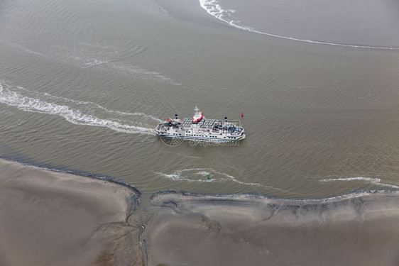 荷兰渡船在WaddenSea的荷兰渡船在WaddenSea通过沙岸之间的小通道低潮航行图片