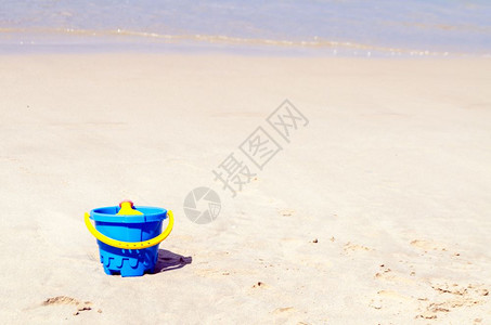 沙海滨上装玩具的婴儿塑料桶图片