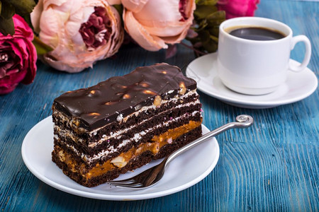 巧克力海绵蛋糕含焦糖的巧克力海绵蛋糕和蓝背景的坚果工作室照片巧克力海绵蛋糕含焦糖的巧克力海绵蛋糕和蓝背景的坚果图片