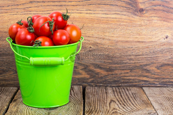 工作室照片樱桃番茄在木桌上的绿色桶中收获木桌上的绿色桶中收获图片