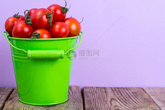 工作室照片樱桃番茄在木桌上的绿色桶中收获木桌上的绿色桶中收获图片
