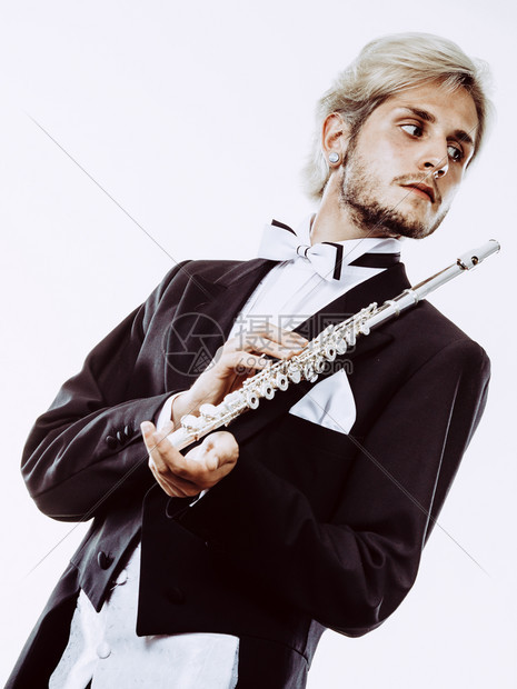 穿尾衣的年轻优雅男子拿着乐器穿尾衣的男风笛手拿着长图片