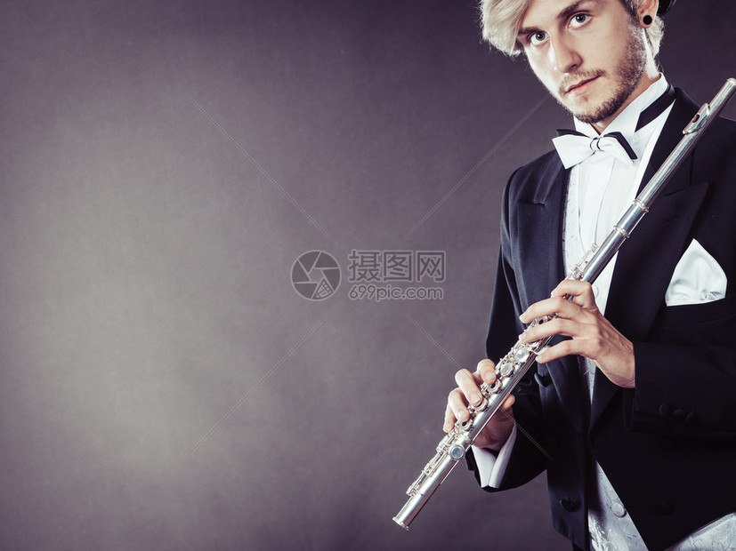 古典音乐激情和爱好概念穿着优雅音乐的金发年轻男子拿着长笛的肖像深灰色背景的演播室拍摄穿着优美服装的音乐家拿着长笛图片