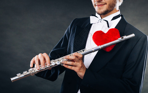 情人节爱旋律概念长笛音乐演奏男吹笛音乐演奏者年轻有乐器和红心的优雅时尚男子长笛和心的男子吹手爱情旋律图片