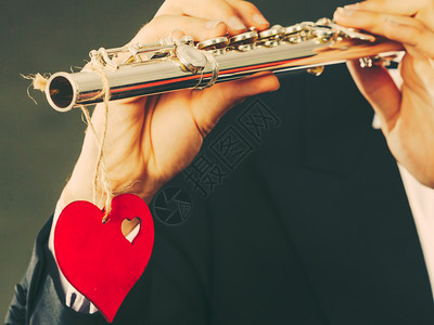 情人节爱旋律概念长笛音乐演奏人吹风的音乐演奏者男手拿着乐器和红心关上门男吹风曲手拿着笛子和心爱旋律图片