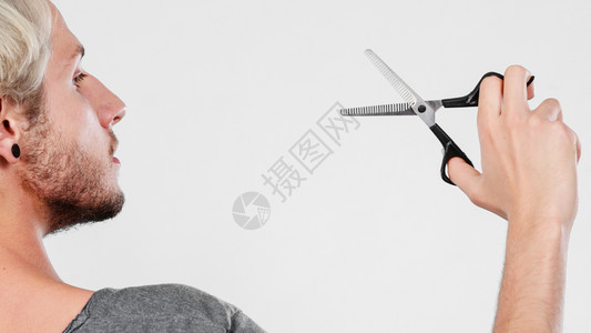 发型和发型年轻帅哥拿着理发师专用的剪子工具男人用剪刀织纹或变薄剪刀图片