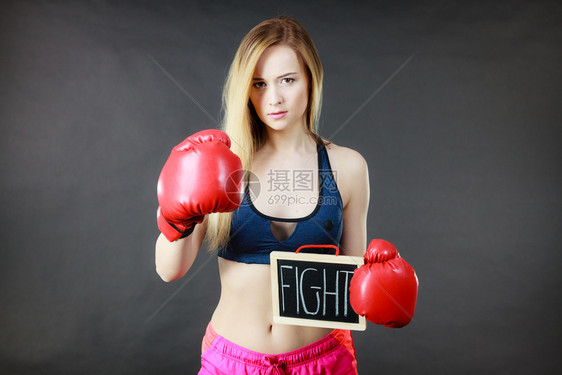 身着拳击手套的年轻运动妇女拿着黑板打斗的文字标志图片