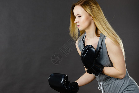 运动技巧竞和健壮的身体年轻女打拳击金发女孩戴黑色拳击手套运动和健身权力锻炼对灰色的侧视拳击女孩用手套练习图片