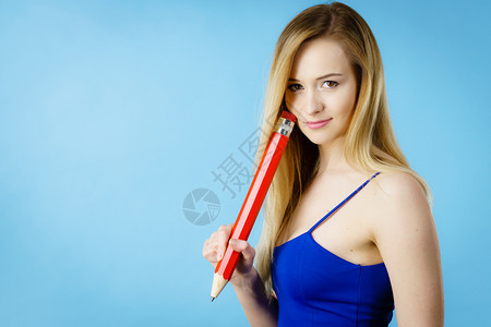 沉迷于思考的女人想寻求解决办法深思熟虑的女学生或提出一个想法持有大红铅笔工作室拍摄蓝色女困惑思考手头拿着大铅笔图片