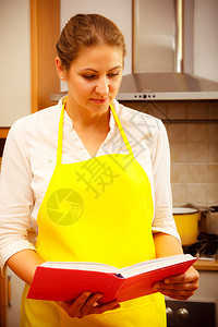 家庭主妇烹饪厨师手持阅读烹饪册寻找食谱中年妇女在厨房里准备食物家庭主妇手持烹饪册在厨房里做饭图片