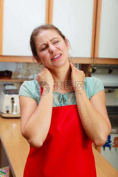 过度劳累的成年妇女因颈部疼痛而受苦在厨房到压力的成年妇女因颈部疼痛而受苦图片