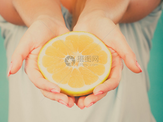 女手上一半的黄葡萄果柑橘水健康饮食体重减值概念图片