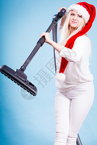 女在屋内吸尘与器清洁者一起戴着圣诞帮手帽子的笑少女圣诞节时间和家务概念与吸尘器清洁者一起戴着桑塔帮手帽子的少女图片