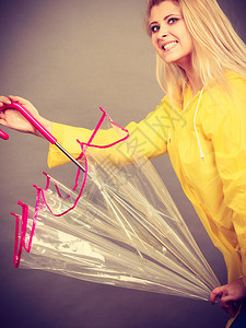 穿着黄色雨衣的金发女子拿着透明的雨伞玩得开心穿着雨衣的女子图片