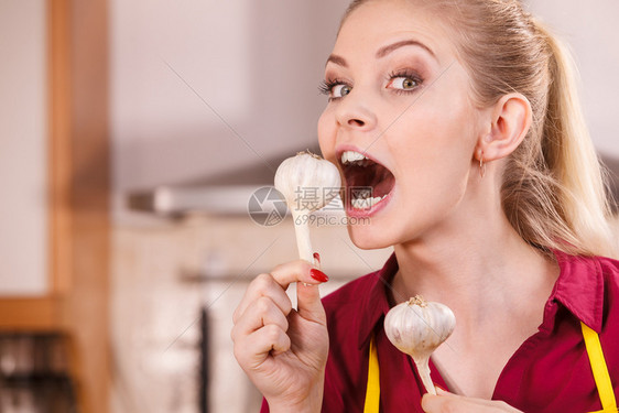 可笑的年轻女人试图吃生大蒜咬口张开有趣的女人咬大蒜吃图片