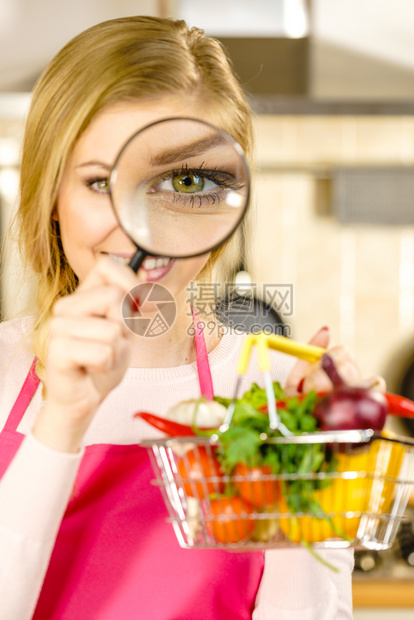 妇女使用放大玻璃槽许多彩蔬菜调查购物篮健康的饮食生活方式营养素食品寻找杀虫剂和化学品图片