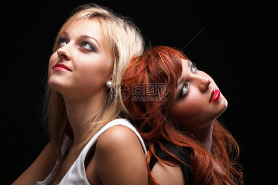 两个快乐的年轻女友金发和红头黑背景图片