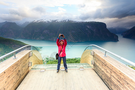 旅游业和旅游业挪威斯堪的纳维亚半岛Stegasteinlookout的女自然旅游摄影师正在用相机拍照欣赏奥兰峡湾风景挪威Steg图片
