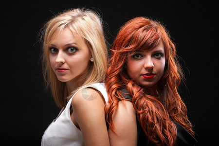 两个快乐的年轻女友金发红头黑背景图片