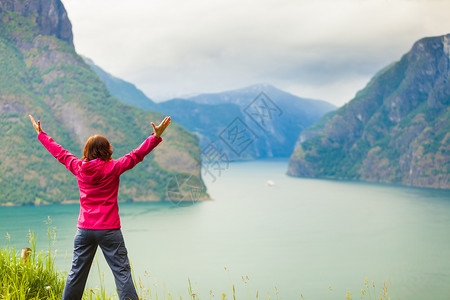 旅行概念自由游妇女快乐享受手举起来望着挪威的fjords山在挪威的Norwegian山码头举起手来的妇女图片