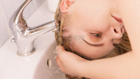 洗头发的女人在浴室水槽里洗长金发在家理的概念洗头女人在浴室水槽里洗头发图片