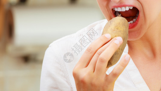 女人吃生土豆食品的紧闭图片