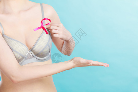 保健医药和乳腺癌意识胸罩中带有粉色丝的妇女做出邀请手势用复制空间保持开放的手胸罩中带有乳腺癌意识的妇女胸罩中带有乳腺癌意识的丝带图片