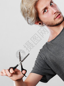 发型和发型年轻帅哥拿着理发师专用的剪子工具男人用剪刀织纹或变薄剪刀图片