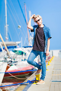 度假放松思想年轻时尚金发男子站在港口附近放松享受美丽的阳光明媚天气外门夏天金发男子站在港口附近图片
