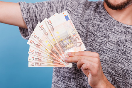 财富金融概念持有50欧元的钞票工作室拍摄蓝背景持有大量欧元货币的人背景图片
