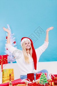 节日礼物季节概念戴圣诞帽的女人坐在沙发上准备圣诞礼物戴圣诞帽准备圣诞礼物的女人图片