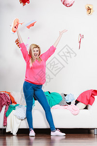 服装两难的概念快乐的女人把衣服往头上扔把房间弄得一团糟快乐的女人在头上扔衣服图片
