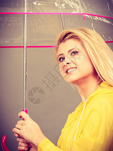 雨天时心情良好金发妇女快乐穿着黄色雨衣拿透明伞戴雨衣伞穿雨衣的妇女快乐穿着透明伞图片