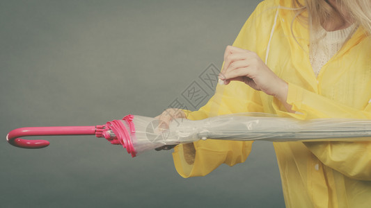 穿着黄色雨衣的女子手持闭着雨伞穿衣的女子手持闭着雨伞图片