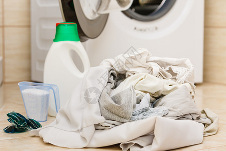 洗粉涤剂和在浴室的机器旁边测量杯子家务衣物洗涤器概念衣粉涤剂图片
