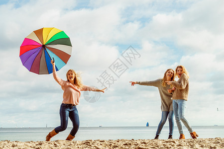 三个充满欢乐的女子在一起玩得很开心一个女人拿着多彩的雨伞女人拿着和朋友玩得开心图片
