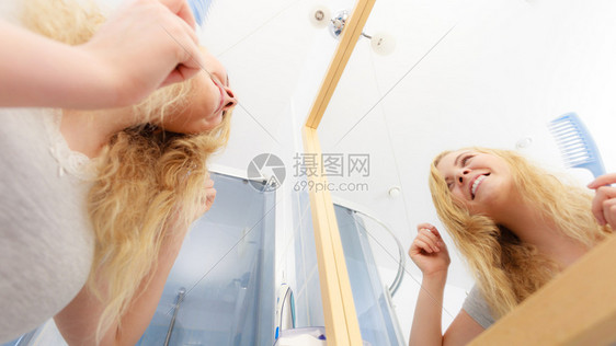 快乐的女士照着镜子看自己身上有湿的金发纯净洁女湿金发图片