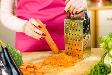 无法辨认的妇女用金属磨草机涂胡萝卜厨房用土豆做食物准备健康的蔬菜沙拉图片